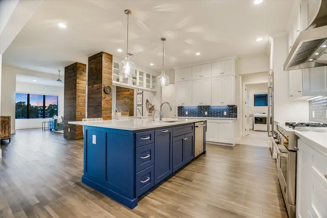 a kitchen with stainless steel appliances granite countertop wooden cabinets a stove a sink and a wooden floors