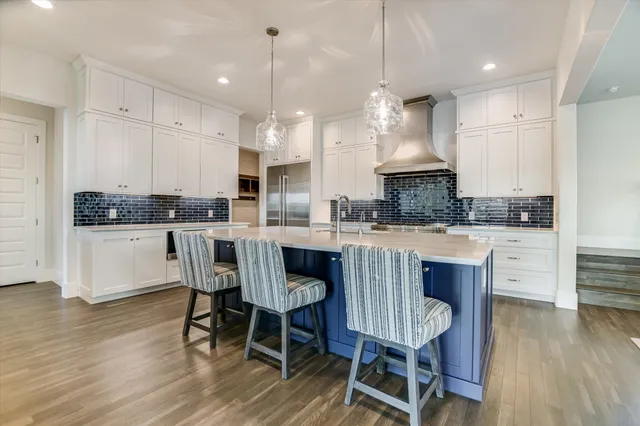 a kitchen with kitchen island granite countertop a dining table chairs and white cabinets