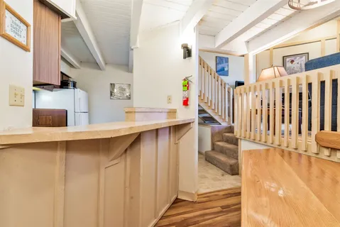 a hallway with a white stove top oven a table and chairs with wooden floor