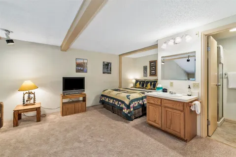 a spacious bedroom with a bed and a tv on the dresser