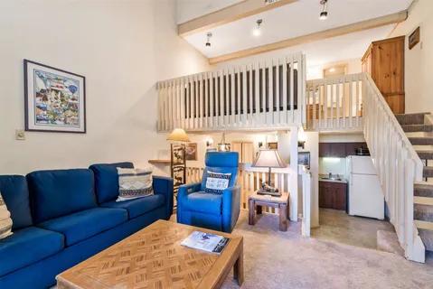 a living room with furniture kitchen view and a wooden floor