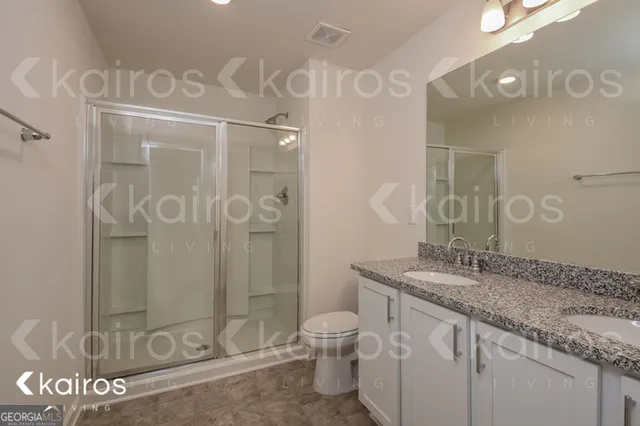 a bathroom with a granite countertop sink mirror vanity and toilet