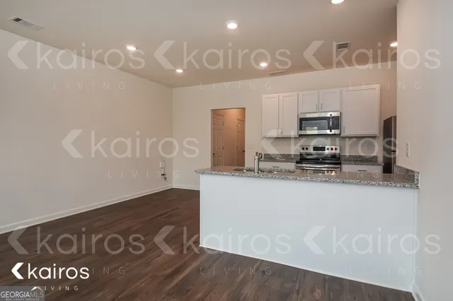 a kitchen with kitchen island granite countertop a sink a stove a refrigerator and a granite counter tops