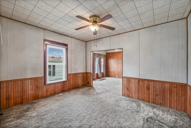 an empty room with ceiling fan and windows