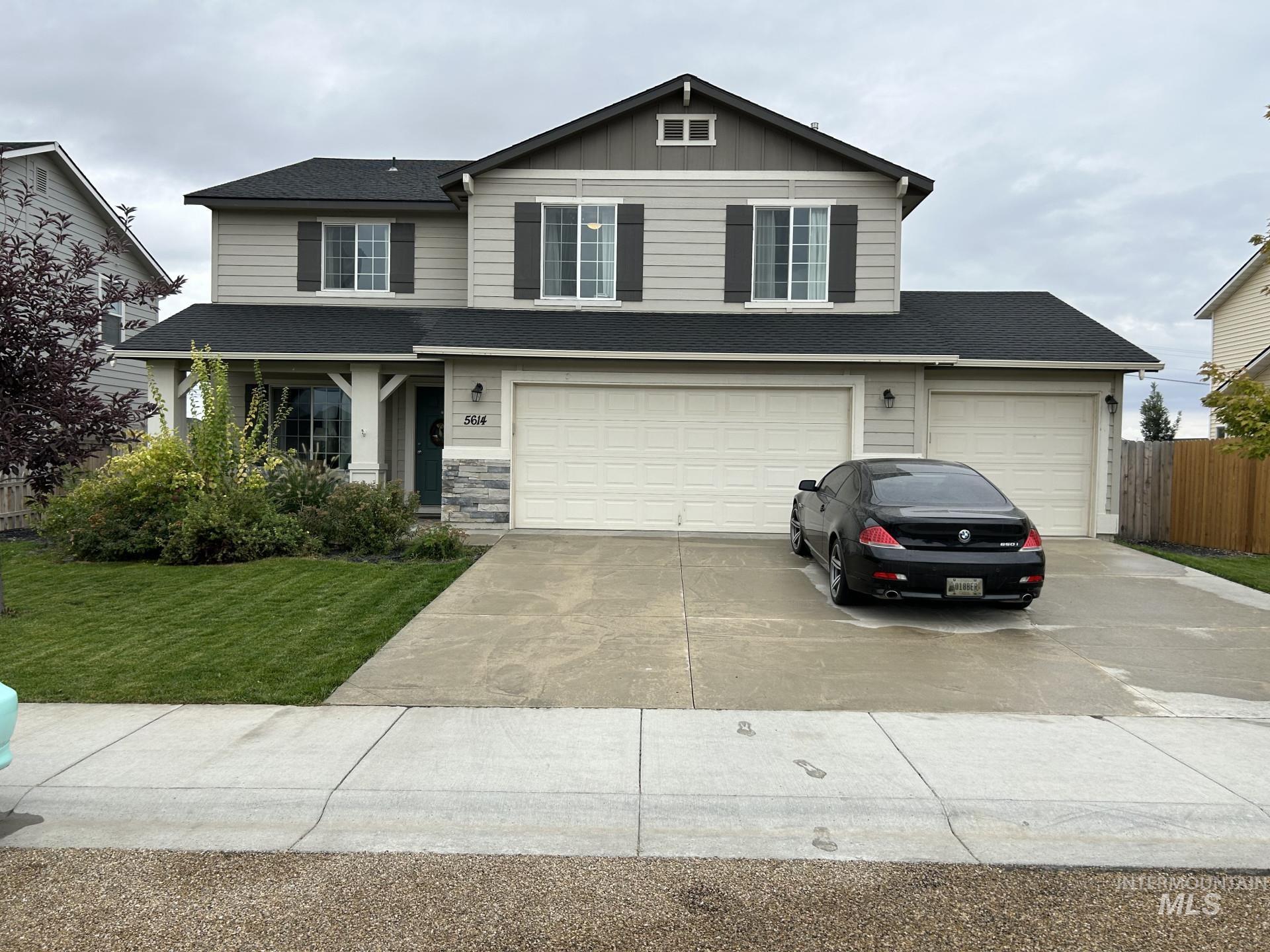 Traditional-style house featuring driveway, board and batten siding, a garage, a shingled roof, and stone siding