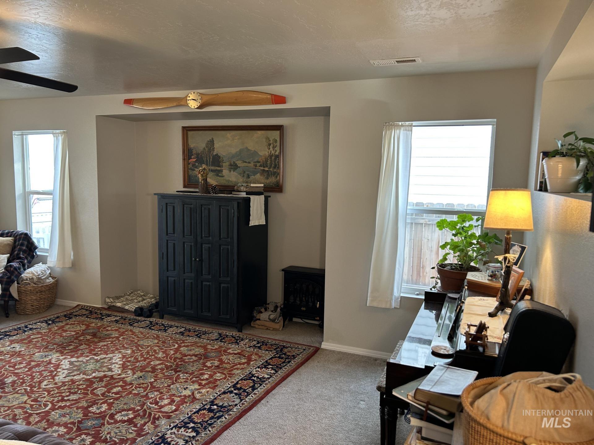 5614 Barkley Way Caldwell, ID 83607 - Photo 12 of 50 Living area with a textured ceiling, carpet floors, healthy amount of natural light, and a ceiling fan