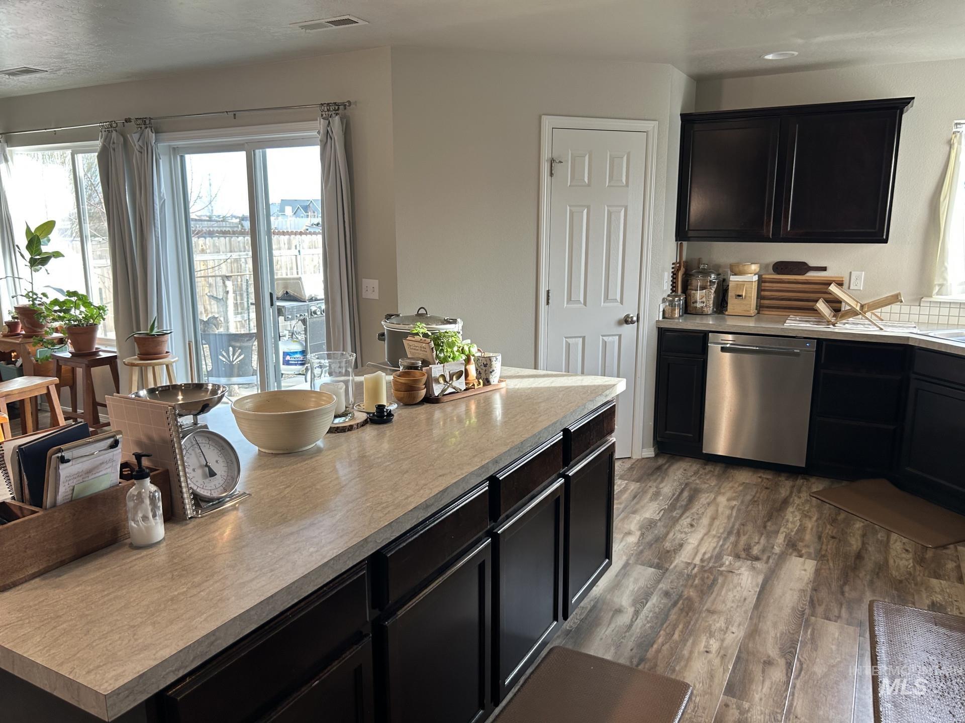 5614 Barkley Way Caldwell, ID 83607 - Photo 22 of 50 Kitchen with dark cabinets, stainless steel dishwasher, light countertops, and dark wood-style floors