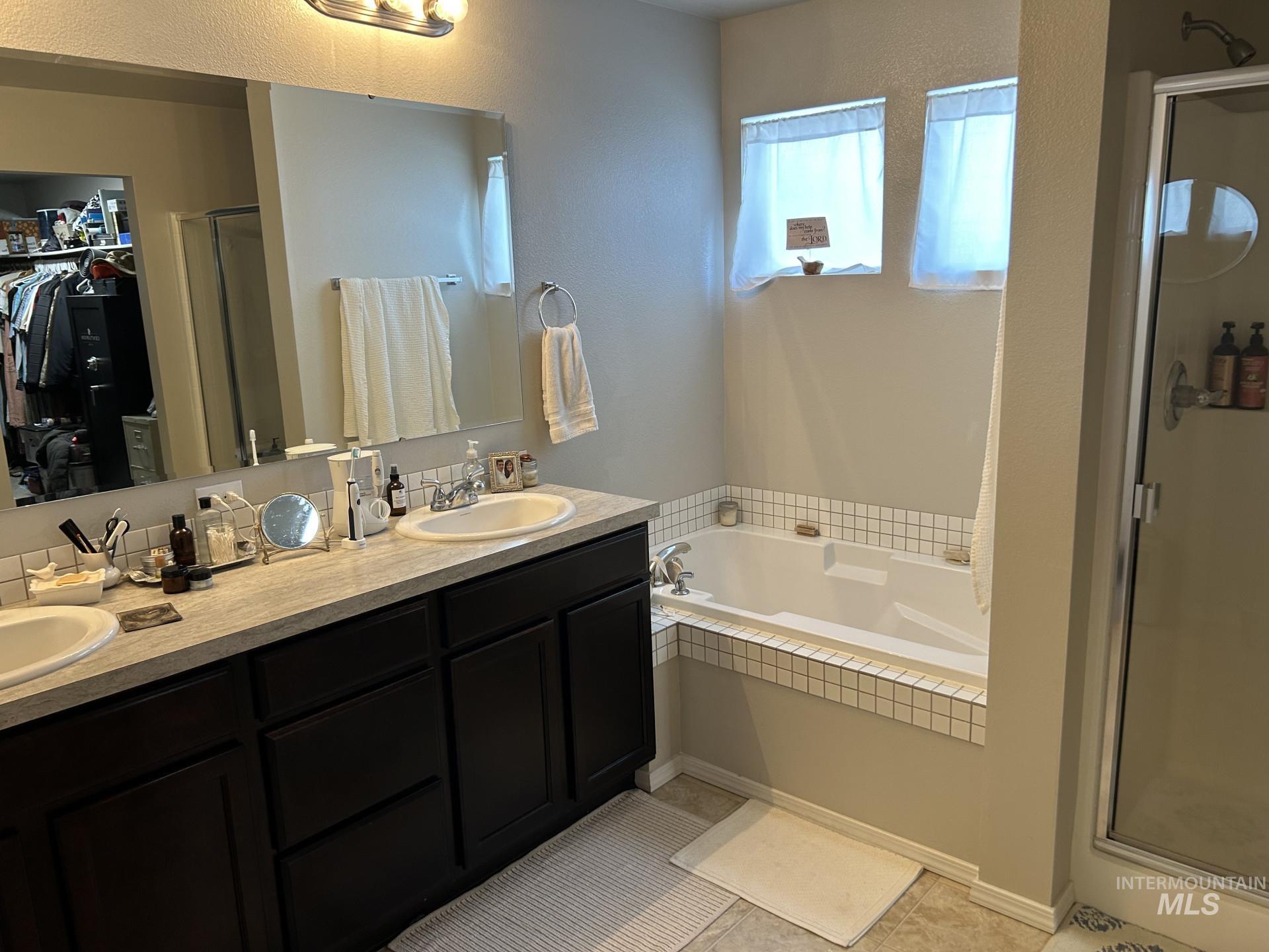 5614 Barkley Way Caldwell, ID 83607 - Photo 41 of 50 Full bath featuring a stall shower, a spacious closet, double vanity, light tile patterned floors, and a bath