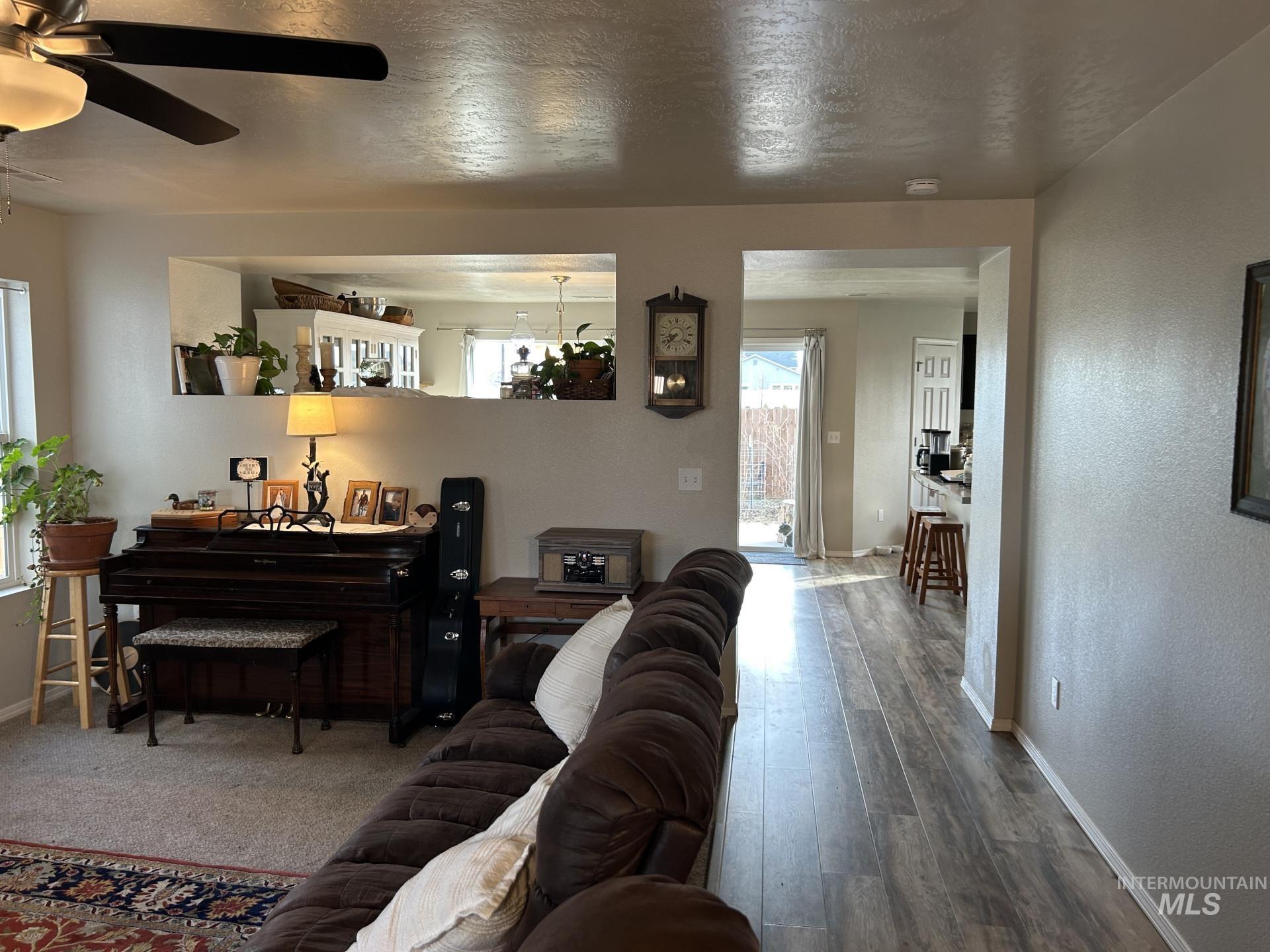 5614 Barkley Way Caldwell, ID 83607 - Photo 10 of 50 Living room with a textured wall, a textured ceiling, a ceiling fan, and wood finished floors