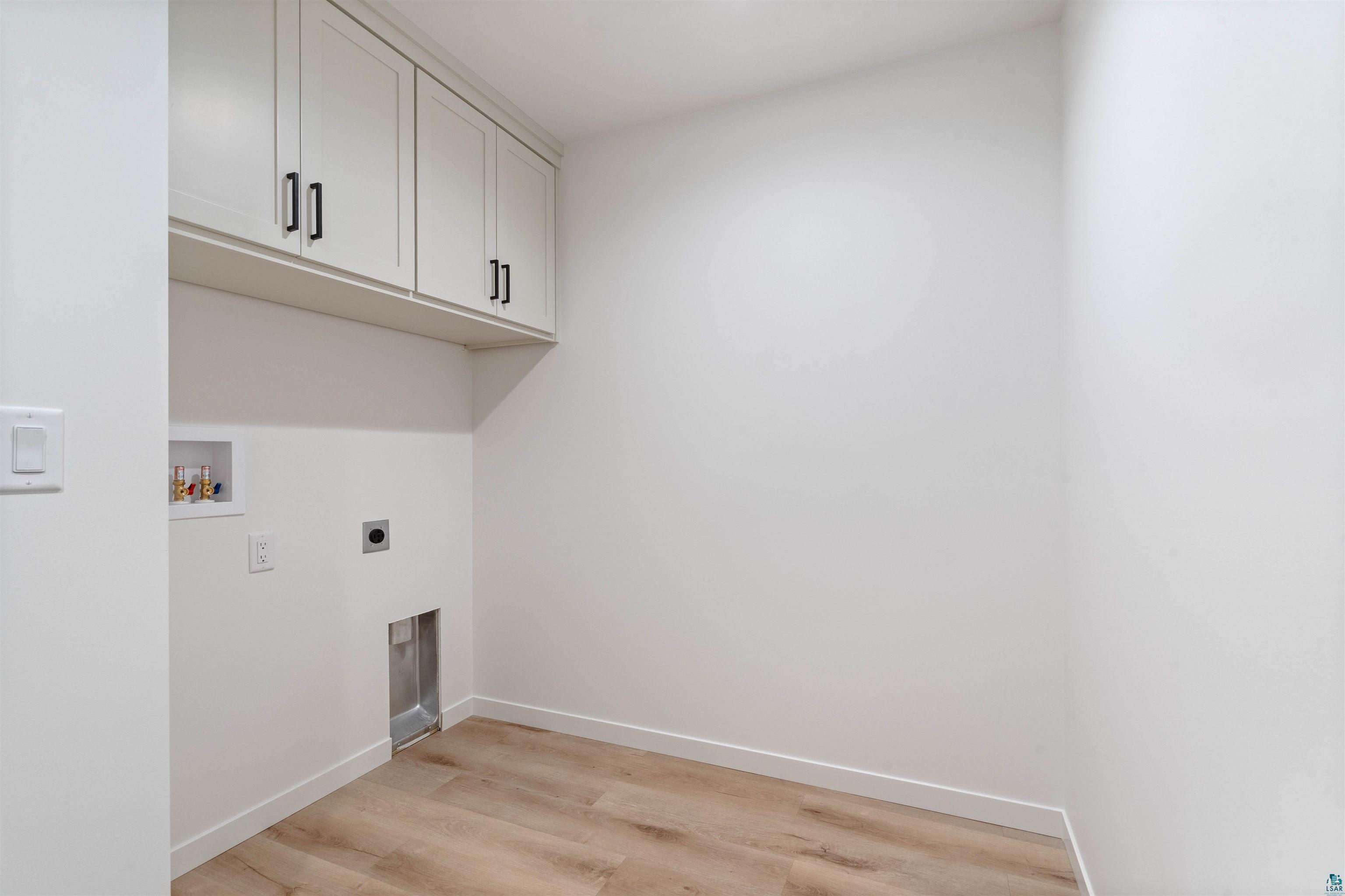 1386 Stephen Road Cloquet, MN 55720 - Photo 21 of 25 Laundry area featuring light wood-finish flooring, white walls, and built-in white cabinetry with dark hardware