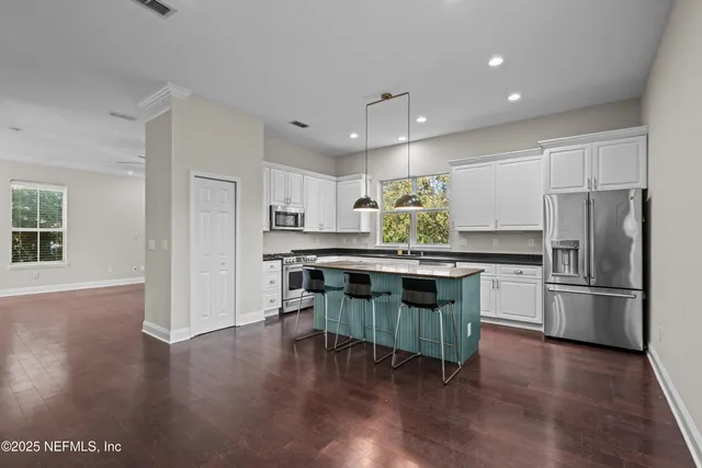 a kitchen with stainless steel appliances granite countertop a refrigerator a stove and a wooden floors