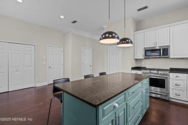 a kitchen with kitchen island granite countertop a table chairs stove and microwave