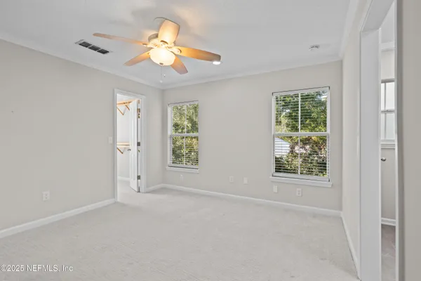 en empty room with windows and chandelier fan