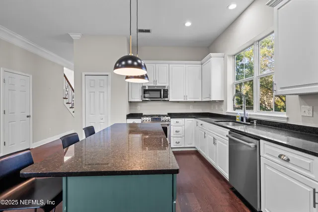 a kitchen with kitchen island granite countertop a sink a center island stainless steel appliances and cabinets