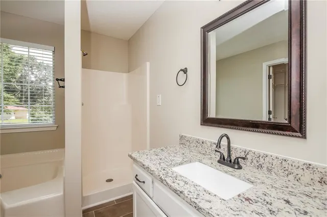 a bathroom with a granite countertop sink mirror and a bathtub