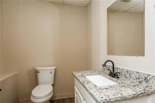 a bathroom with a granite countertop sink toilet and mirror