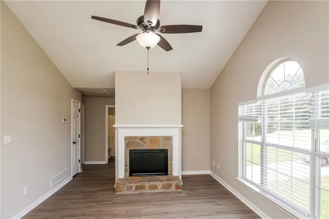 a view of a livingroom with a fireplace wooden floor and windows