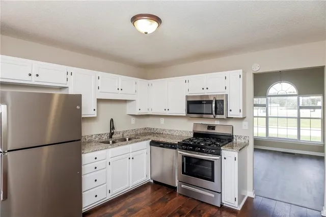 a kitchen with cabinets stainless steel appliances and wooden floor