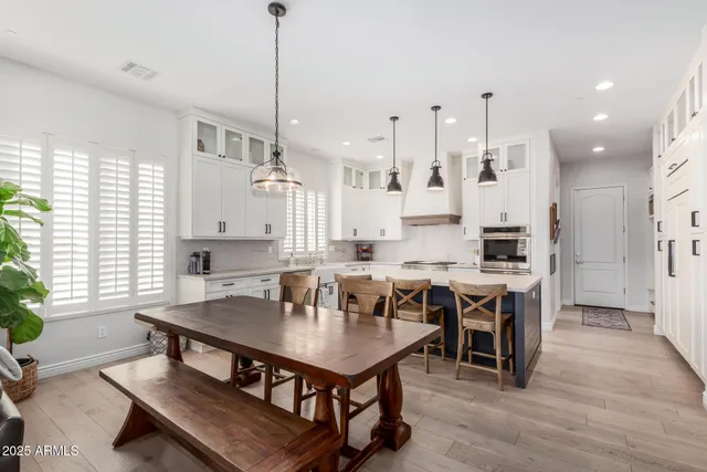 a kitchen with stainless steel appliances a stove a sink a refrigerator a center island and a wooden floor