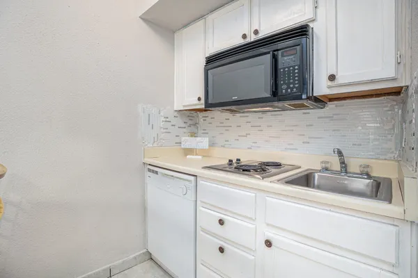 a kitchen with granite countertop white cabinets sink and stainless steel appliances