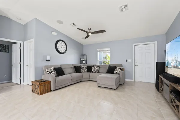 a living room with furniture a clock tv and a ceiling fan