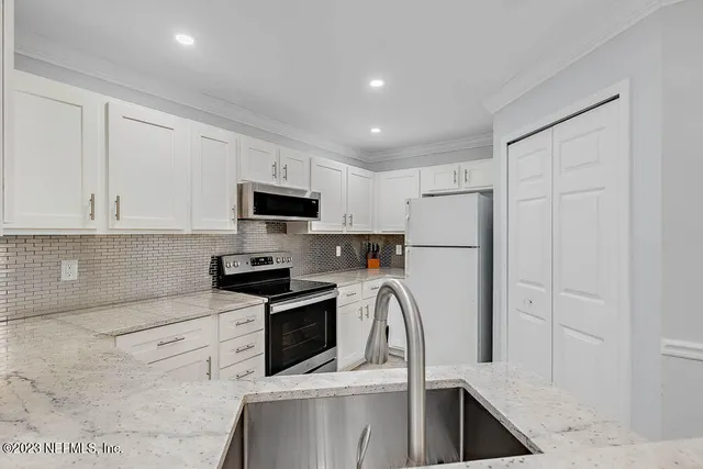 a kitchen with white cabinets sink and stainless steel appliances