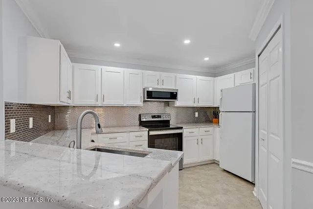 a kitchen with stainless steel appliances granite countertop a refrigerator sink and white cabinets