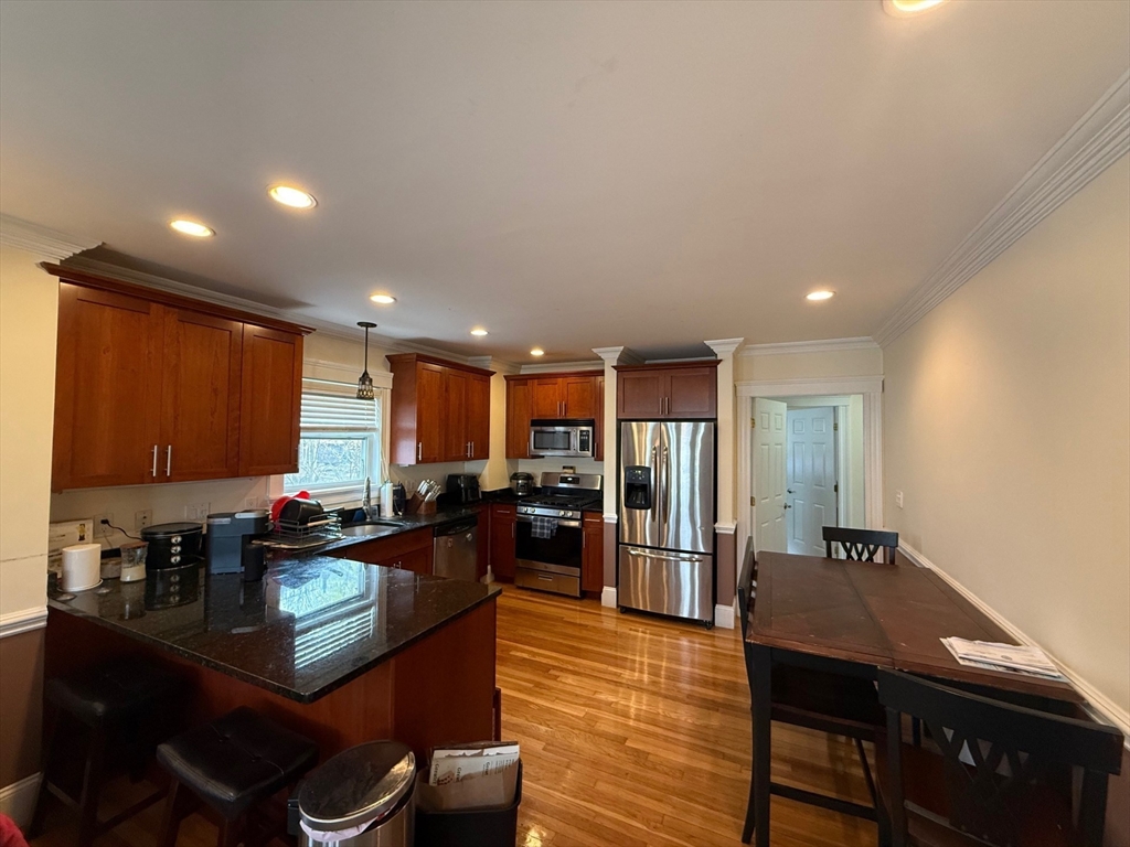 72 Bennett Street, Unit 72 Boston, MA 02135 - Photo 3 of 17 a kitchen with stainless steel appliances granite countertop a stove a refrigerator a sink a dining table and chairs with wooden floor