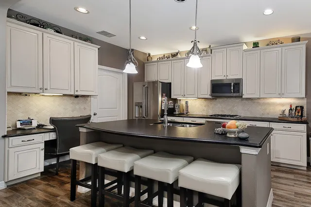 a kitchen with kitchen island granite countertop a table chairs a sink dishwasher refrigerator and microwave