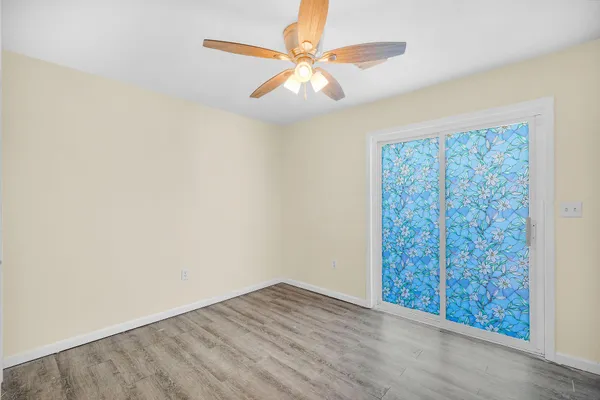 an empty room with windows and fan