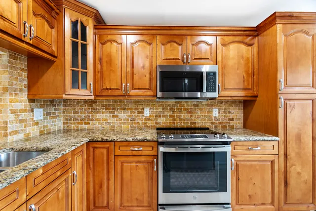 a kitchen with granite countertop a stove top oven microwave and cabinets