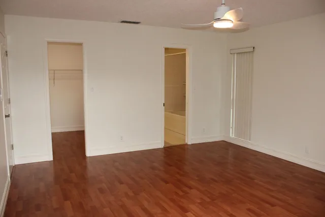 an empty room with wooden floor and windows