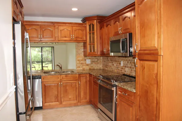 a kitchen with stainless steel appliances granite countertop a stove a sink and a refrigerator