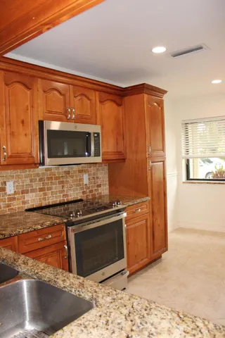 a kitchen with stainless steel appliances granite countertop a stove a sink and a microwave