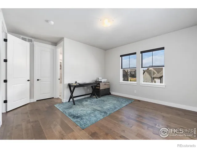 a view of an empty room with window and hardwood floor