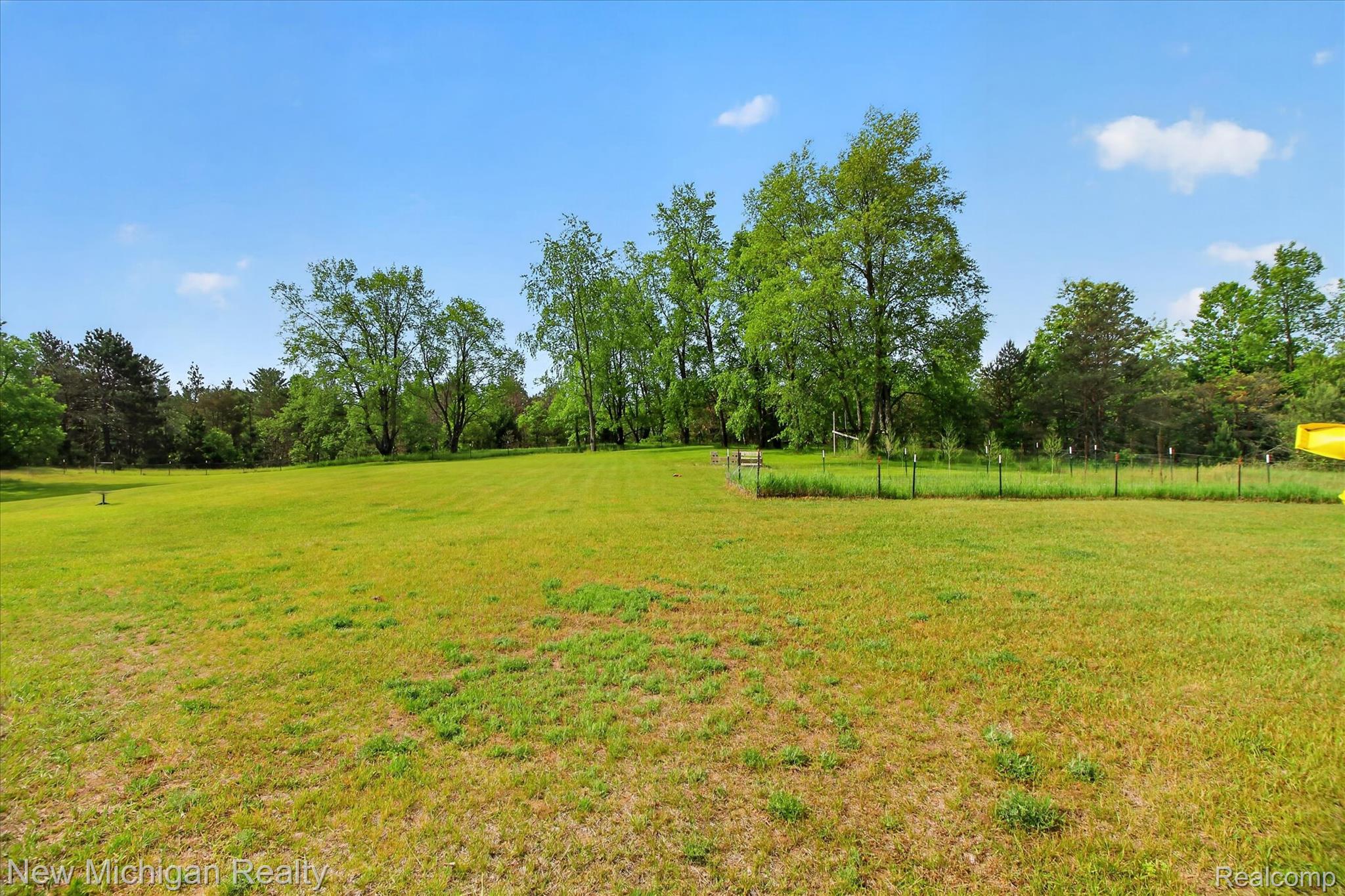 22623 11 Mile Road Reed City, MI 49677 - Photo 44 of 47 Expansive green lawn surrounded by mature trees, featuring a fenced garden area