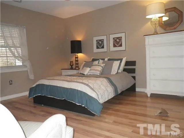 a bedroom with a bed lamp and wooden floor