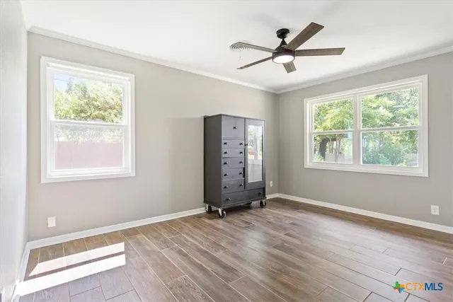 a view of an empty room with a window and wooden floor