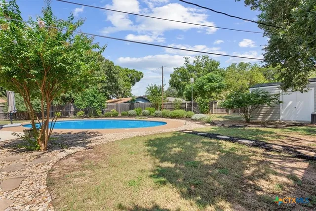 a view of a backyard with large trees and wooden fence