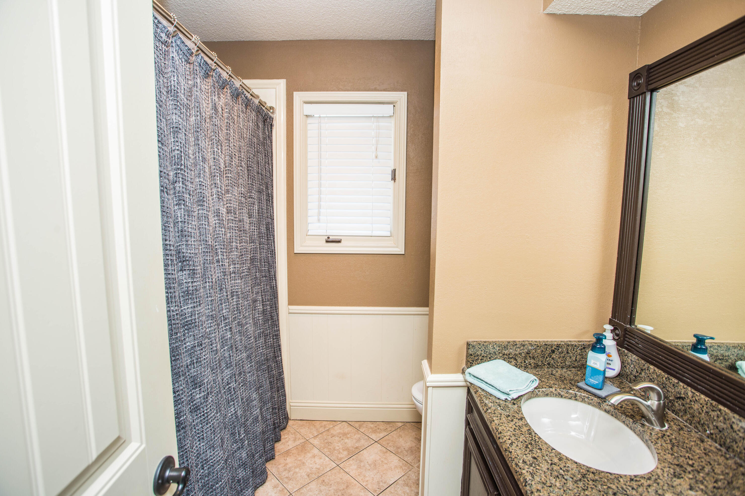 5202 85th Street Lubbock, TX 79424 - Photo 27 of 40 a bathroom with a granite countertop sink a toilet and a mirror