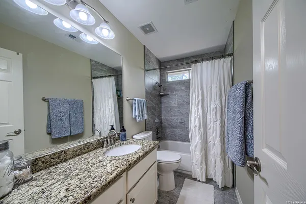 a bathroom with a granite countertop sink toilet and shower