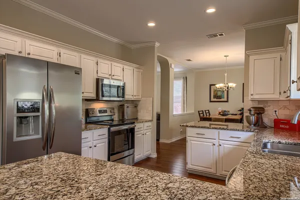 a kitchen with stainless steel appliances kitchen island granite countertop a refrigerator stove and sink