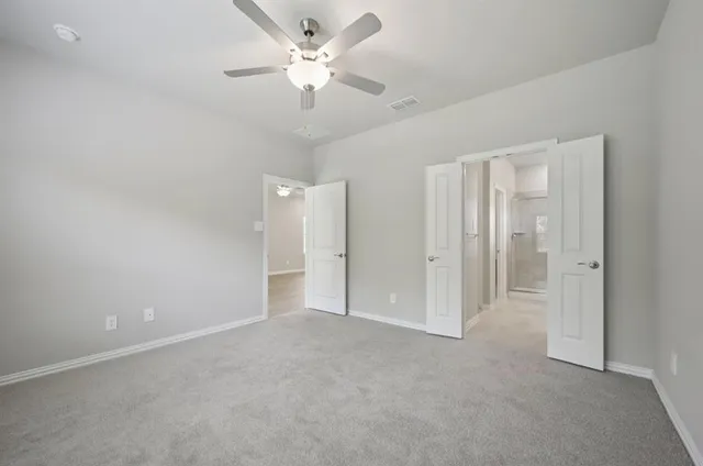 an empty room with a ceiling fan and a bathroom