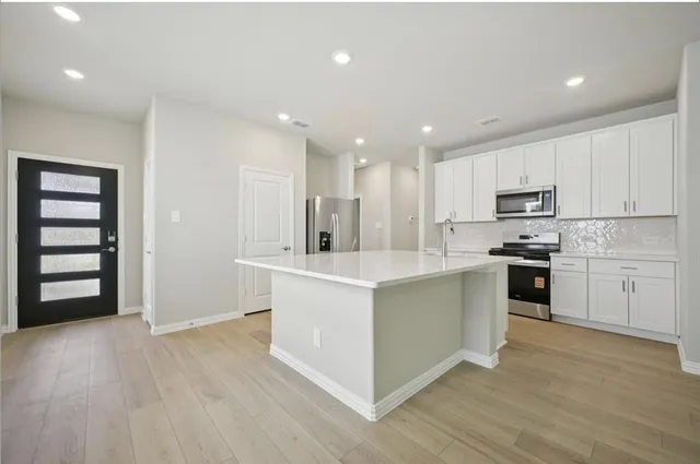 a kitchen with stainless steel appliances granite countertop a stove a sink and a refrigerator