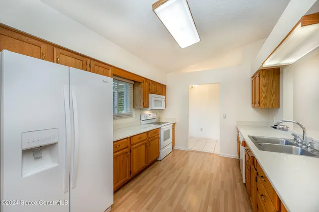 a large kitchen with a sink and wooden floor