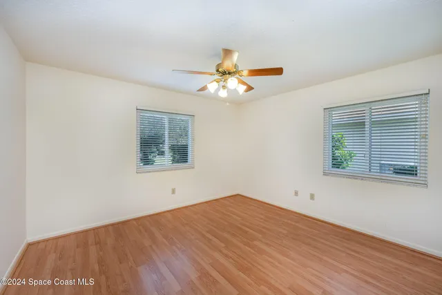 a view of a big room with wooden floor and a chandelier fan