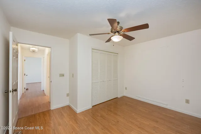 an empty room with wooden floor and fan