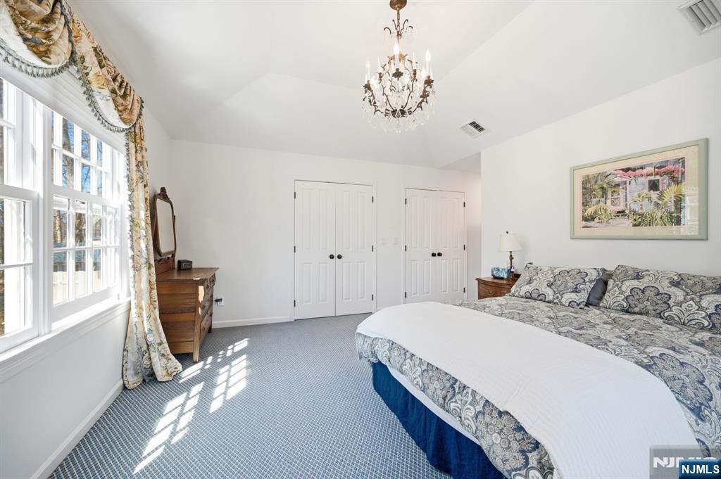 760 Rivenwood Road Franklin Lakes, NJ 07417 - Photo 39 of 48 a spacious bedroom with a bed and a chandelier