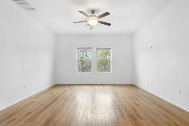 an empty room with wooden floor and windows