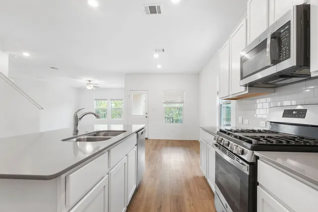 a kitchen with stainless steel appliances granite countertop a sink a stove and cabinets